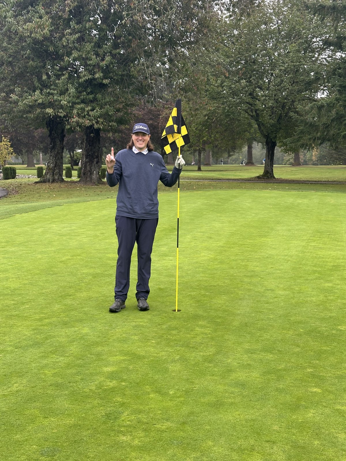 Trevor Johnson holding the flagstick on the green after a hole-in-one at Mount Si, 2025